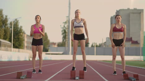 A-group-of-women-at-the-track-and-field-competition-warm-up-and-prepare-for-the-race.-Concentrating-on-the-start-line-at-the-stadium